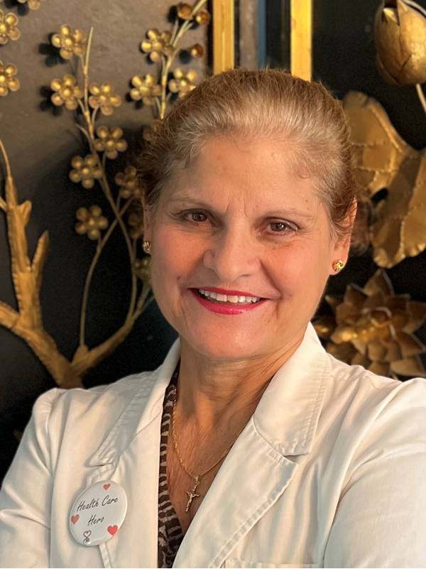 A woman in white shirt and necklace smiling.